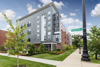 an apartment building with a sidewalk and a street sign in front of it at 310 at Nulu Apartments-Student, Louisville